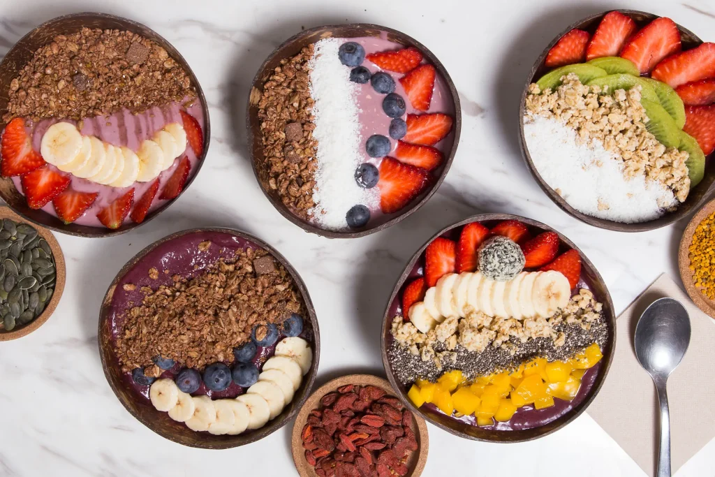 Açaí bowls topped with granola, banana, strawberries, blueberries, coconut and chia seeds